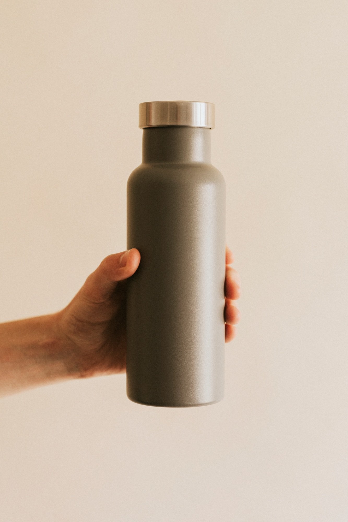 Hand holding gray water bottle mockup